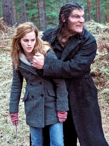 a man and woman walking in the woods with one holding his hand on her shoulder