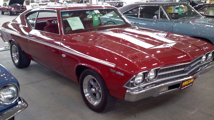 an old red car is on display in a showroom next to other classic cars