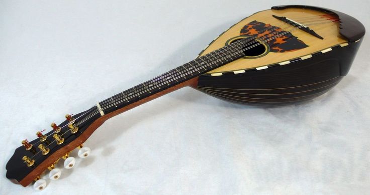 a small wooden instrument sitting on top of a white sheet covered floor with an intricately decorated neck