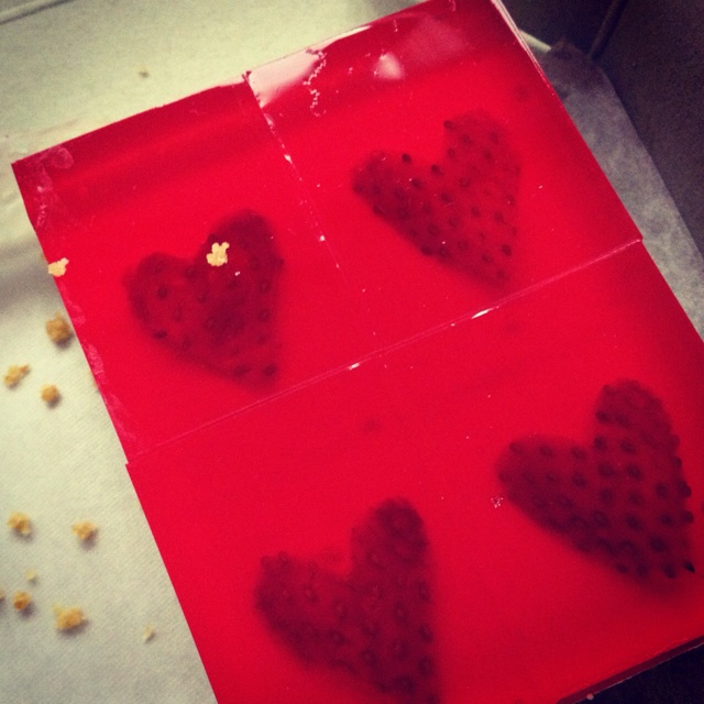 four pieces of heart shaped chocolate sitting on top of a red plastic tray next to nuts