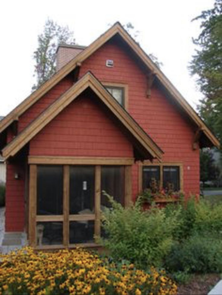 an image of a red house with yellow flowers in the front yard and landscaping around it