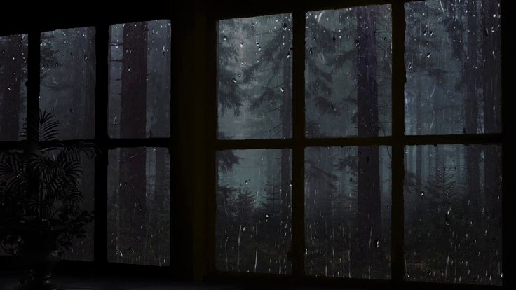 an open window in a dark room with rain falling on the windows and trees outside