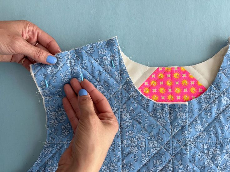 two hands are working on a piece of fabric that has been made into a dress