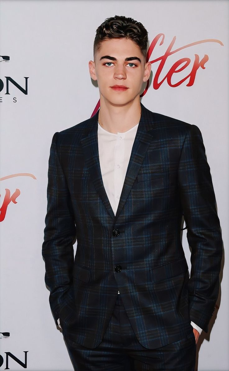 a young man in a suit and tie posing for a photo on the red carpet