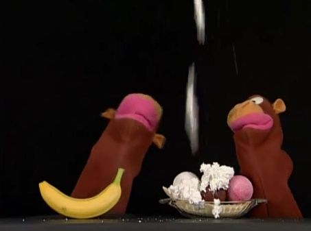 two stuffed animals sitting next to each other in front of a bowl of ice cream