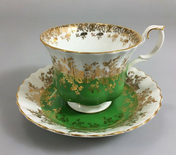 a green and gold tea cup with saucer