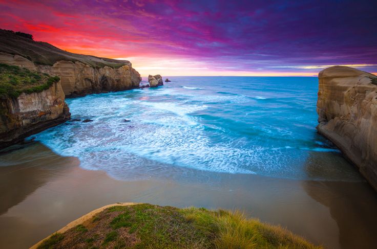 the beach is next to some cliffs at sunset