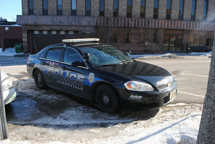 a police car is parked in the snow near a building and parking lot with no one around it