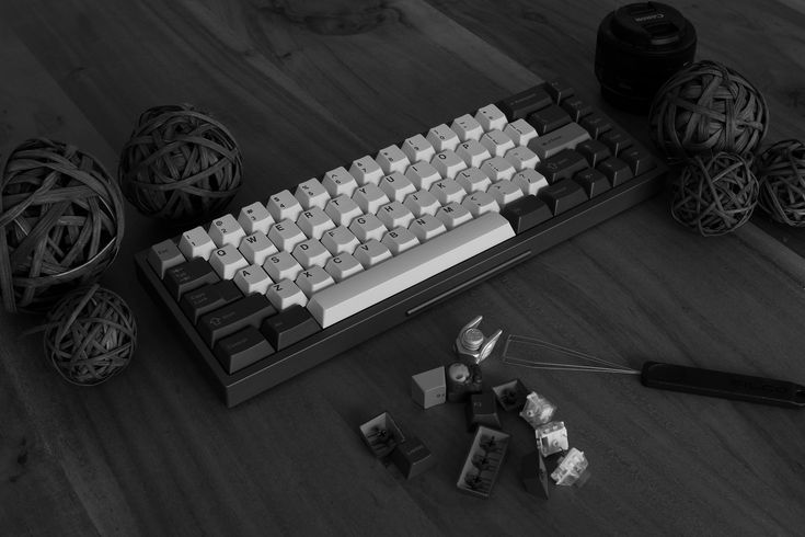 a computer keyboard sitting on top of a wooden floor next to balls of thread and scissors