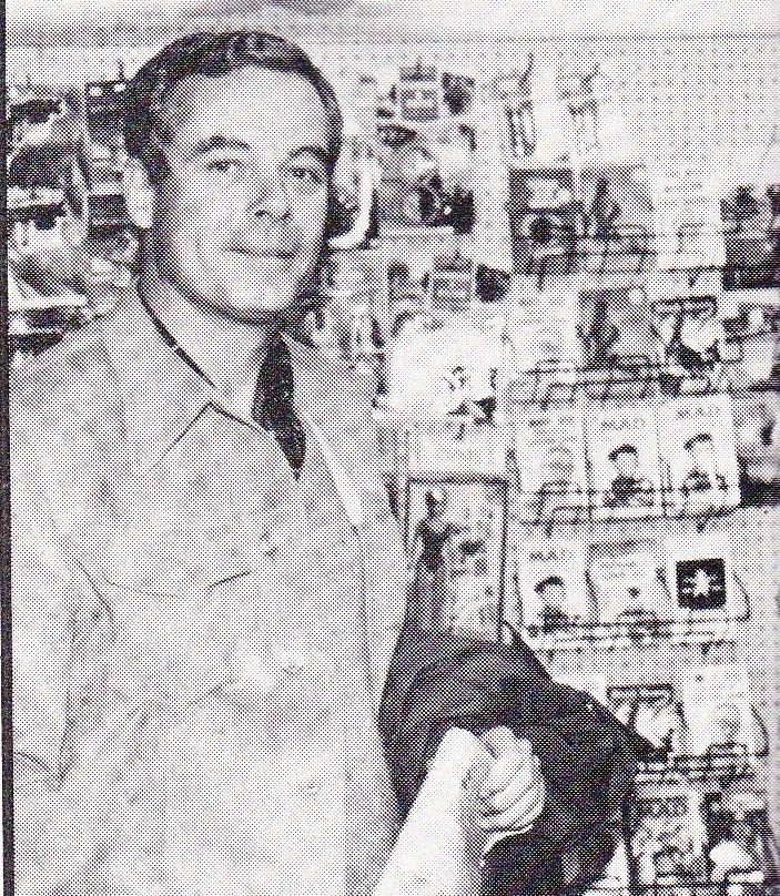 a man standing in front of a wall with pictures on it