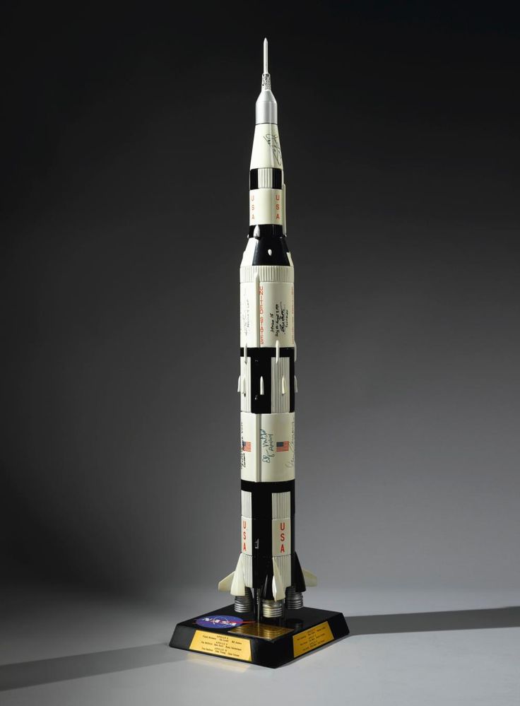 a model of a rocket with writing on the bottom and sides, sitting on a black surface