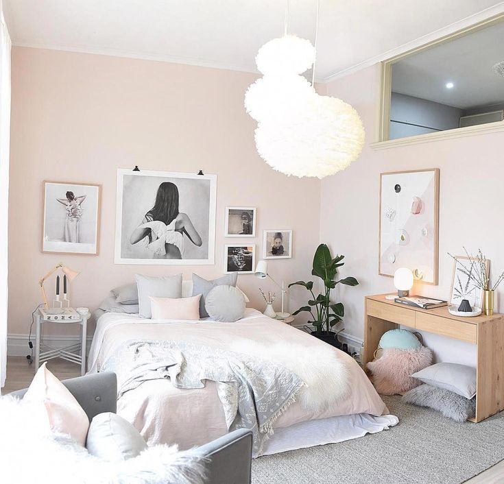 a white bedroom with pink walls and pictures hanging on the wall above the bed,