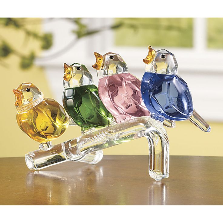 three colorful glass birds sitting on top of a wooden table