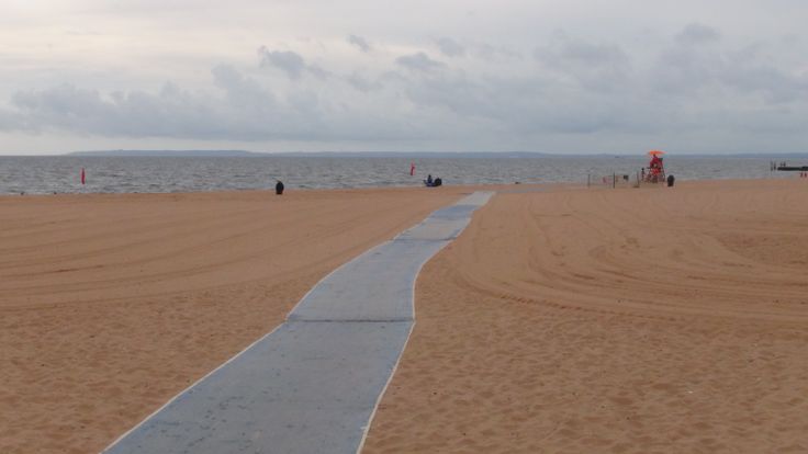 there is a long path going to the water on the beach in front of some people