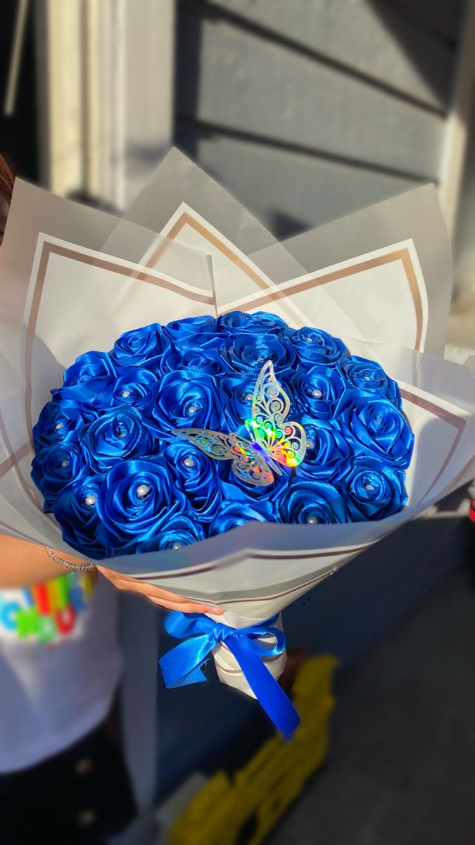 a bouquet of blue roses in a paper wrapper with a butterfly on the top