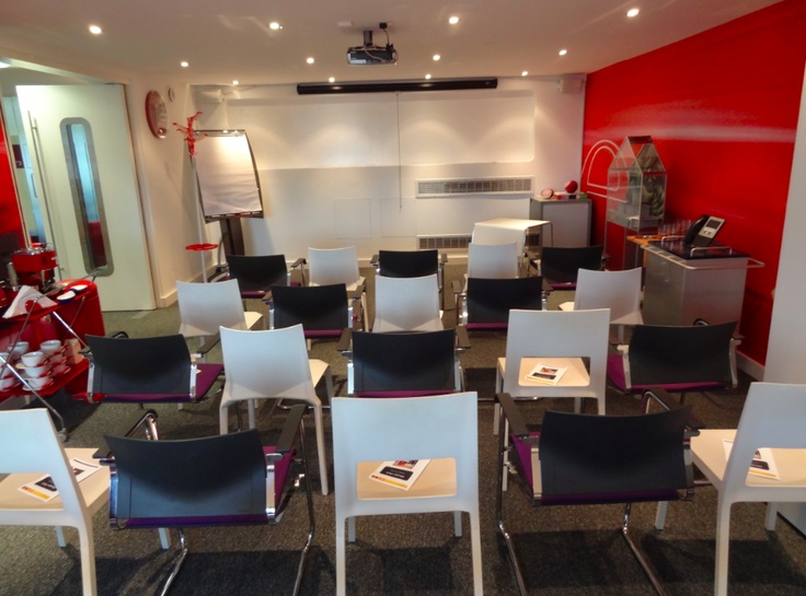 an empty classroom with white chairs and red walls