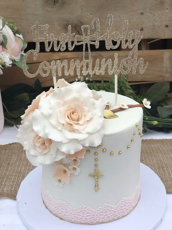 a white cake with flowers and a wooden sign that says first birthday commutish