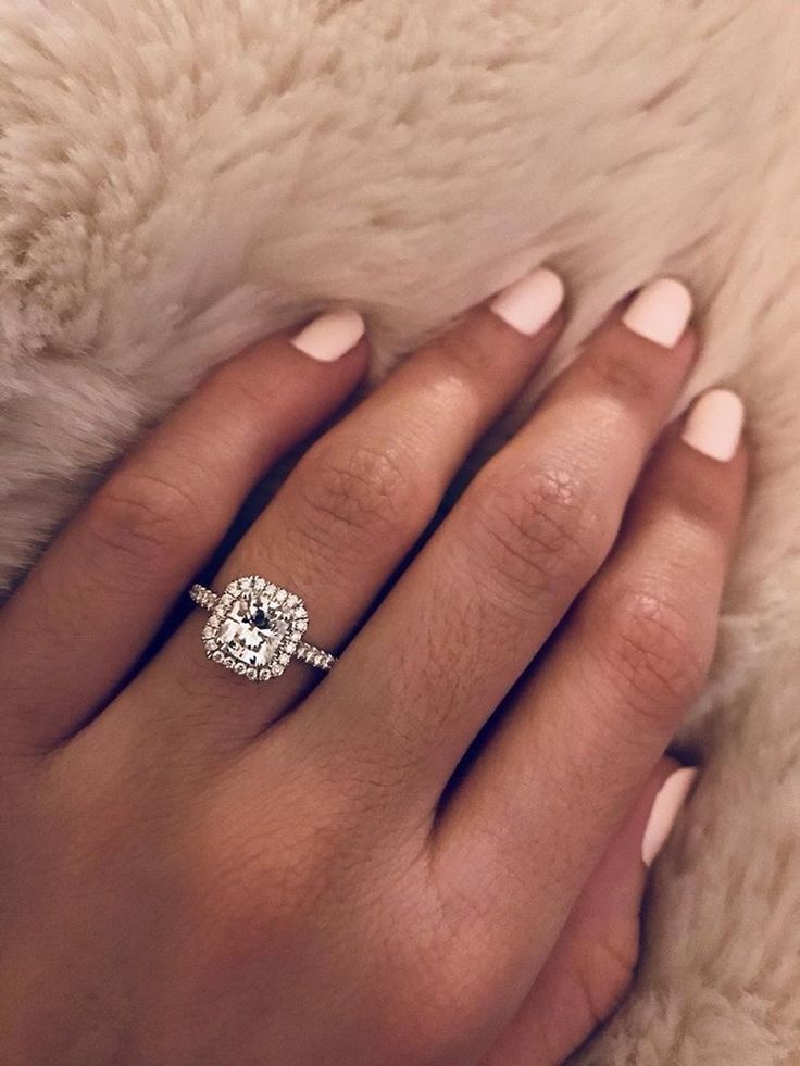 a woman's hand with a diamond ring on top of her finger, and a fur