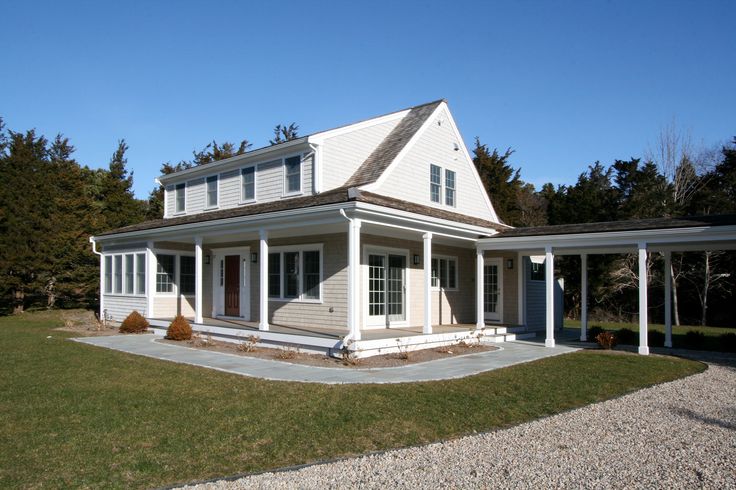 a large white house sitting on top of a lush green field next to a forest