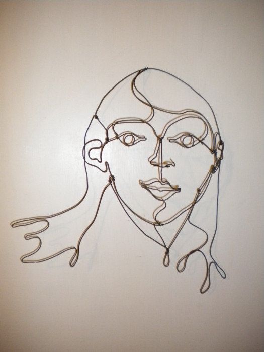 a wire sculpture of a woman's face on a white wall