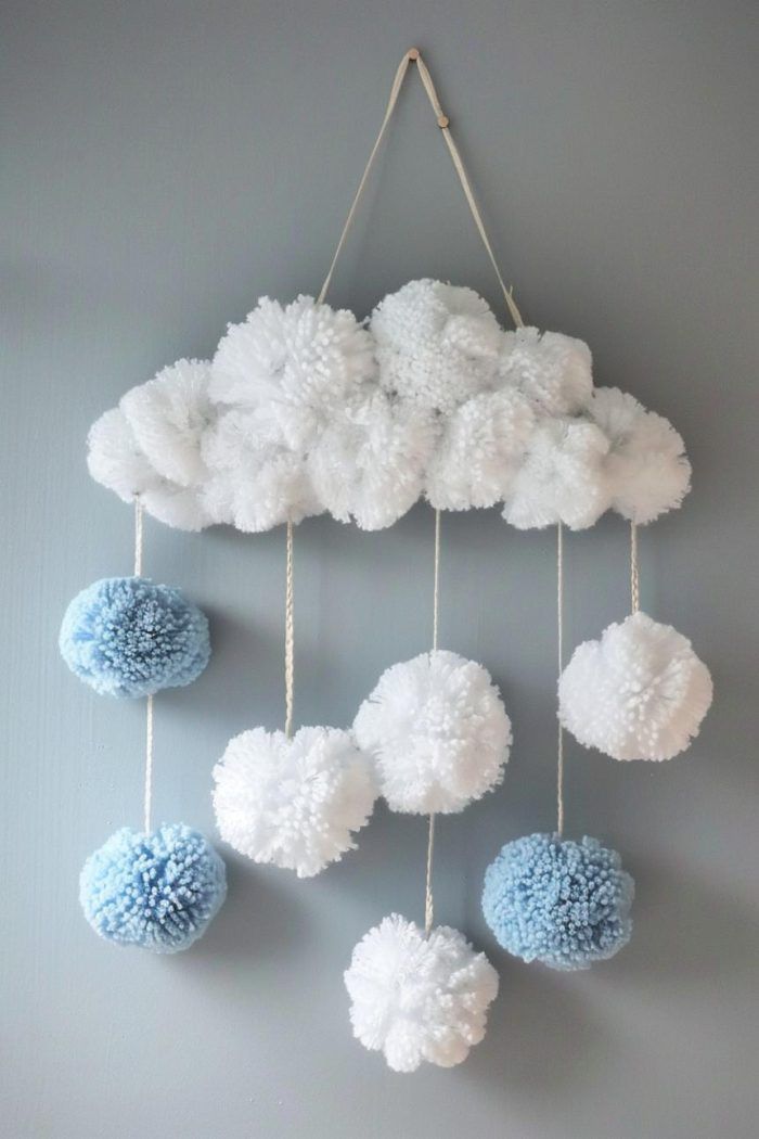 a white and blue wall hanging with pom - poms in the shape of clouds