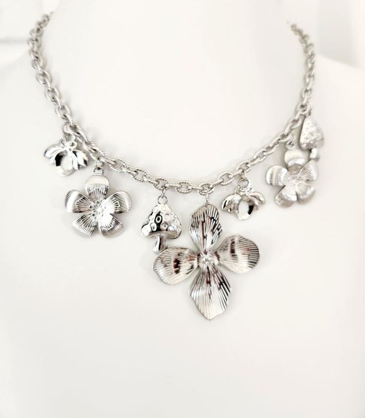 Add a touch of nature-inspired elegance to your jewelry collection with our Multi Charm Silver Necklace. This trendy piece features a delightful combination of flower, mushroom, and bee charms, each meticulously crafted to bring a whimsical charm to your ensemble. Product Details: Material: High-quality stainless steel for durability and a long-lasting shine Charms: Features multiple charms including flowers, mushrooms, and bees Style: Trendy and versatile, perfect for any occasion Whether you'r Nature-inspired Jewelry With Flower Charm, Metal Flower Charm Necklaces, Silver Necklace With Nature-inspired Flower Charm, Silver Nature-inspired Necklace With Flower Charm, Nature-inspired Flower Charm Pendant Necklace, Metal Jewelry With Flower Charm And Pendant, Nature-inspired Silver Flower Necklace With Charm, Flower Charm Necklaces With Flower Pendant For Jewelry Making, Silver Flower Charm Necklaces