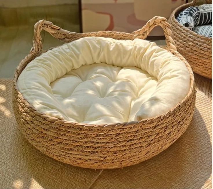 two wicker baskets sitting on top of a floor next to each other with white sheets in them