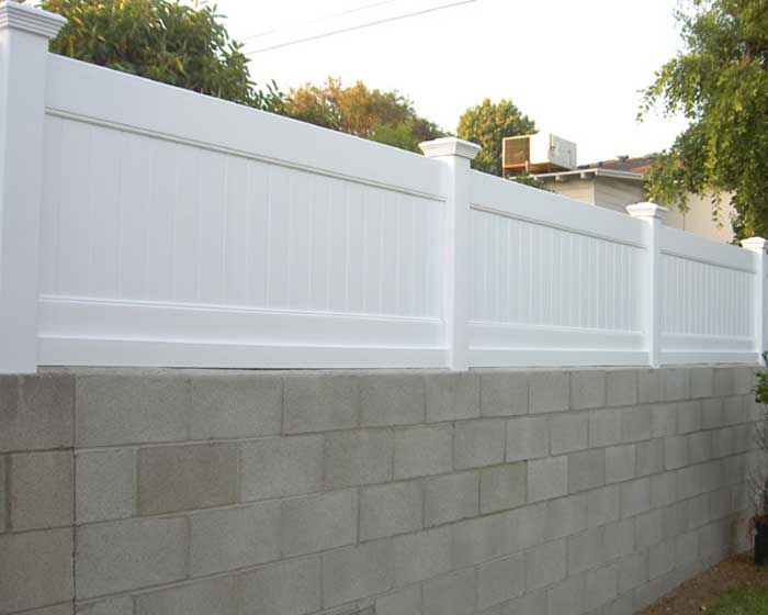 a white picket fence next to a brick wall