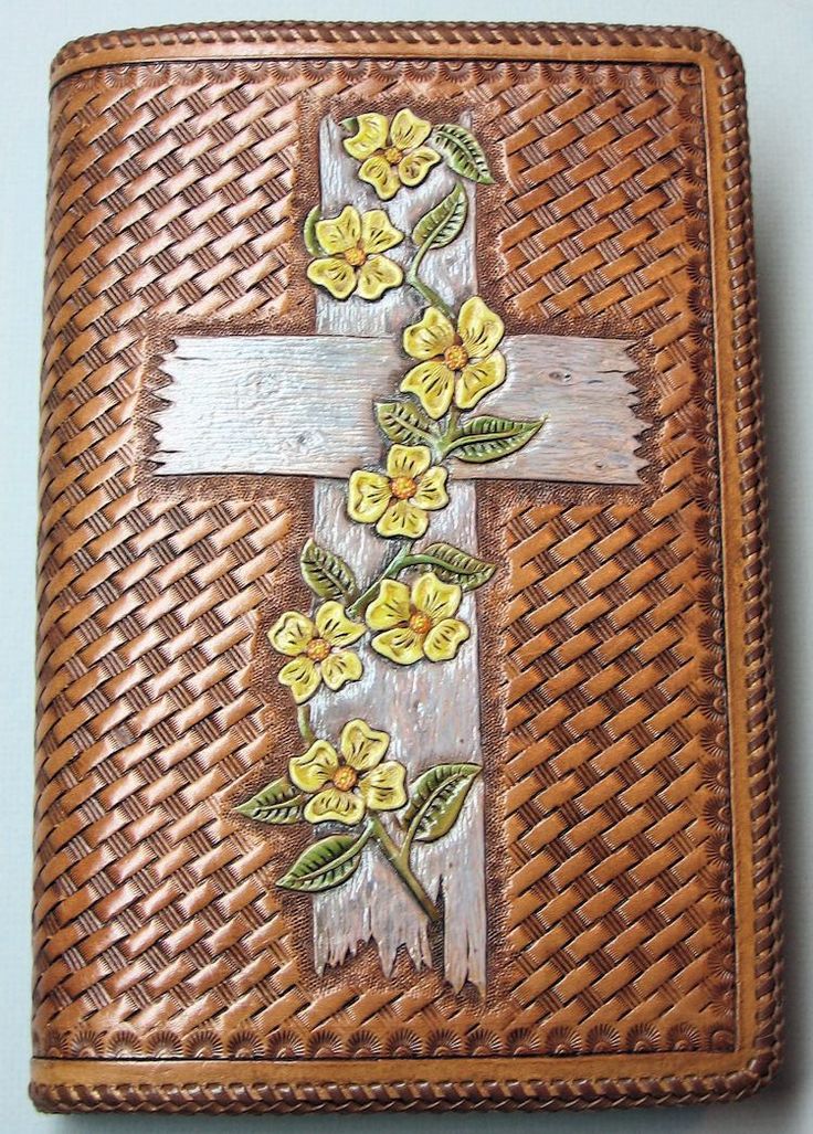 a wooden cross with flowers on it sitting on top of a woven basket next to a wall