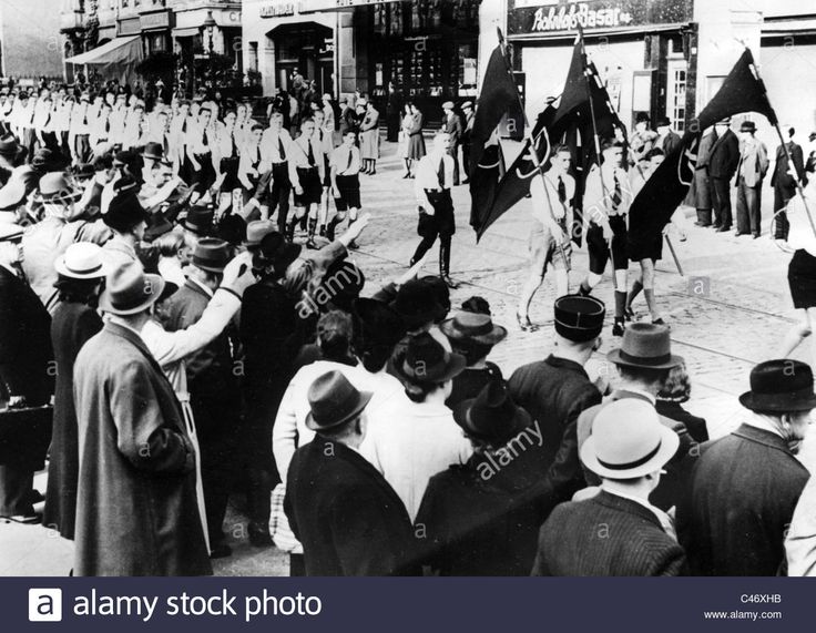 an old black and white photo of men in uniform marching down the street with flags