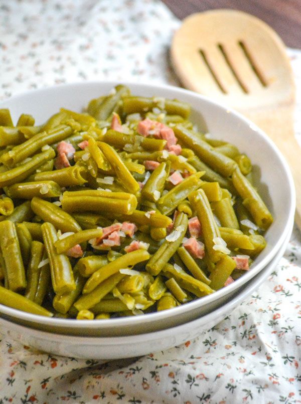 a white bowl filled with green beans and ham