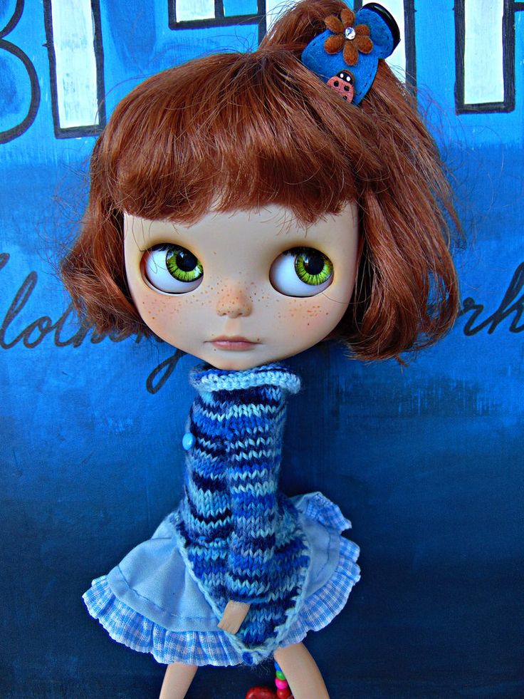 a close up of a doll with red hair and green eyes wearing a blue dress