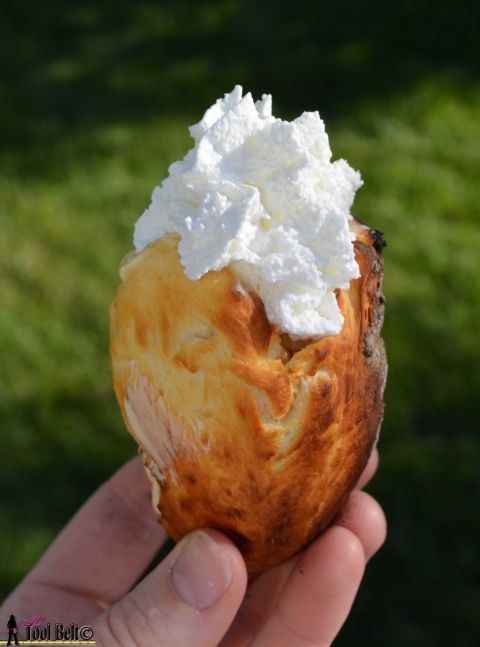 a person holding up a pastry with whipped cream on it's top in their hand