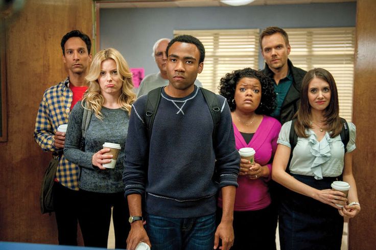 a group of people standing around each other holding coffee cups and looking at the camera