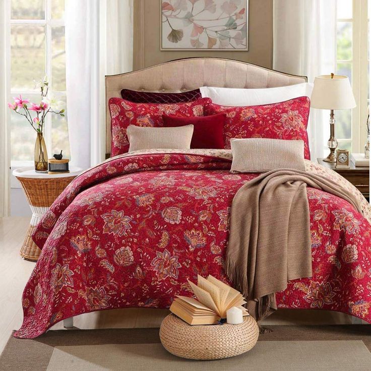 a bed with red comforter and pillows in a room