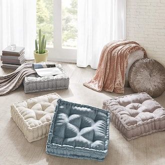 four square dog beds on the floor in front of a window