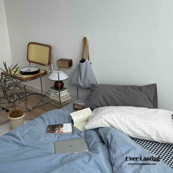 an unmade bed with blue sheets and checkered bedspread in a bedroom