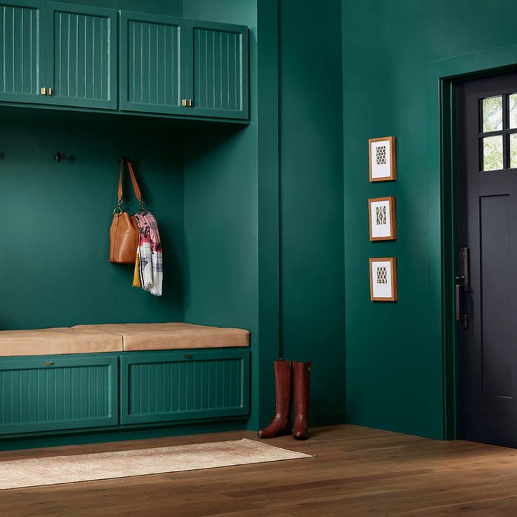 a room with green walls, wooden flooring and two brown boots on the bench