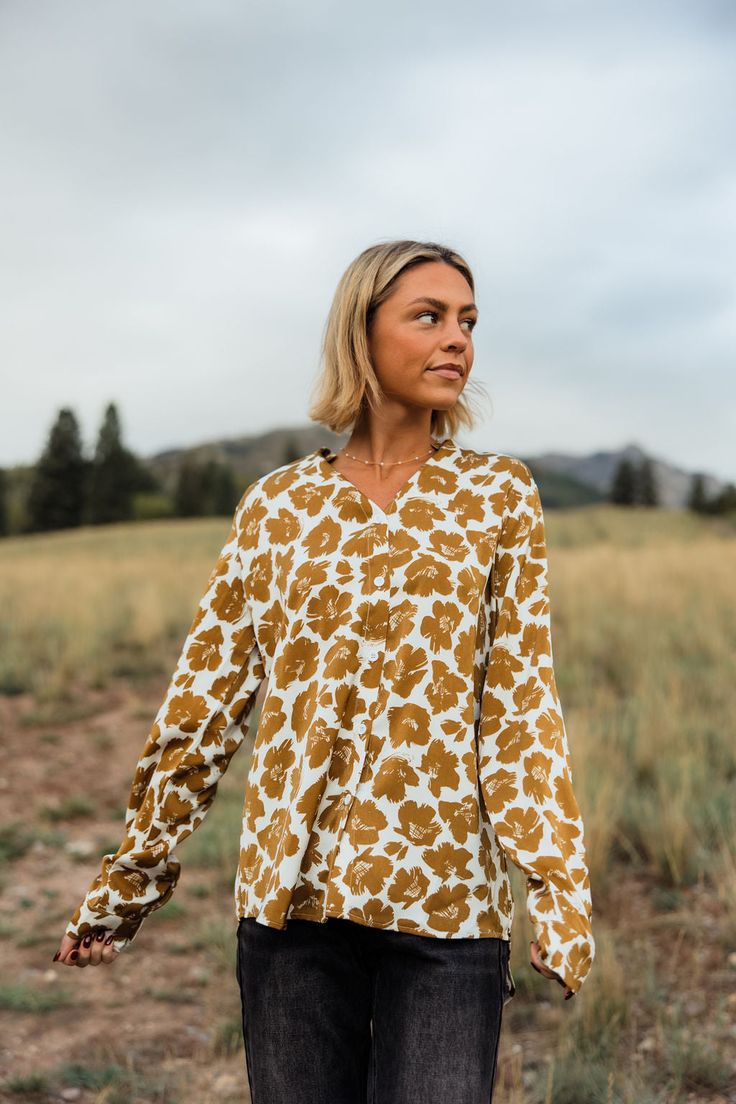 THIS SALE ITEM IS FINAL SALE! Experience effortless style with our Rowen Top-Golden Floral! This relaxed fit top features a button down design, collared neckline, and button cuffs for added versatility. The stunning floral pattern adds a touch of femininity to any outfit. Elevate your wardrobe with this must-have piece.(One model has collar tucked in) *Relaxed fit* Material Content: 100% Polyester Material Pattern: Floral Reagan is 5’5” wearing a small Model Measurements: Reagan Height: 5'5" // Fall V-neck Blouse With Placket, Spring Relaxed Fit Blouse With Placket, Relaxed Fit Blouse With Placket For Spring, Spring Split Neck Blouse With Placket, V-neck Top With Placket For Fall, Floral Print Blouse With Collared Neckline For Work, Workwear Blouse With Floral Print And Collared Neckline, Fall Rayon Blouse With Relaxed Fit, Relaxed Fit Floral Print Button-up Blouse