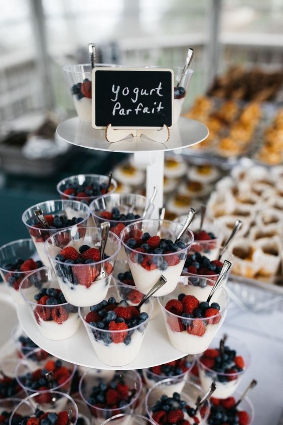 an assortment of desserts and pastries displayed on a table with a sign that says yogurt parfait