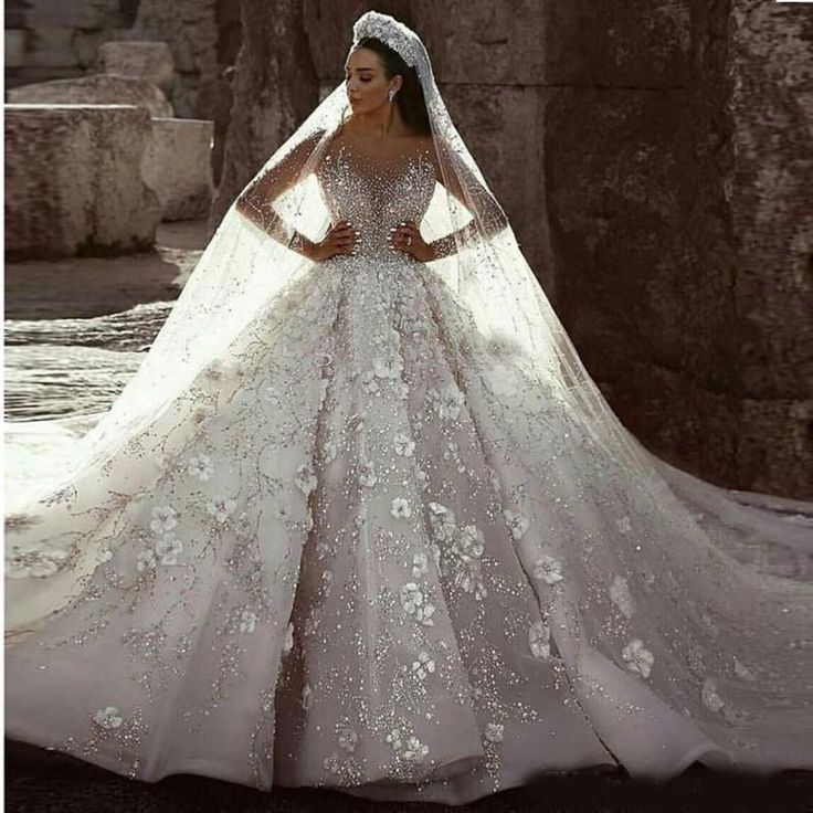 a woman in a wedding dress with flowers on the skirt and veil, posing for a photo