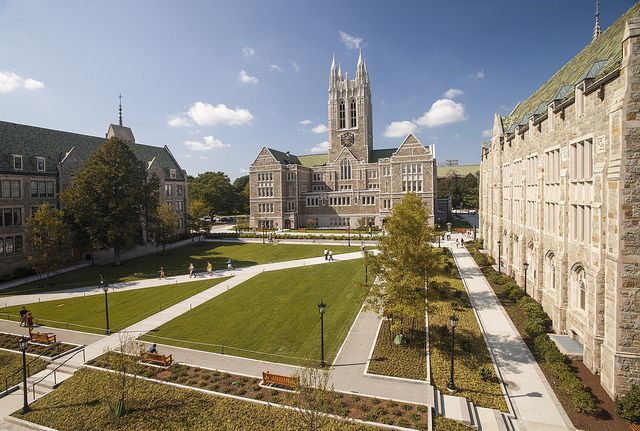 an aerial view of a large building with a lawn in the foreground and people walking around it