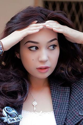 a young woman is holding her hands to her head while wearing a jacket and bracelet