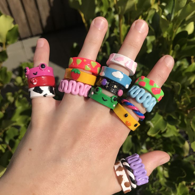 a hand with five different colored bracelets on it's fingers and one is wearing an animal print ring