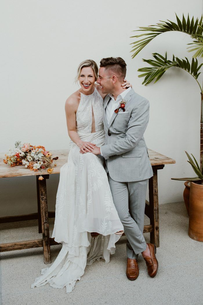 a bride and groom pose for a photo in front of a table with potted plants