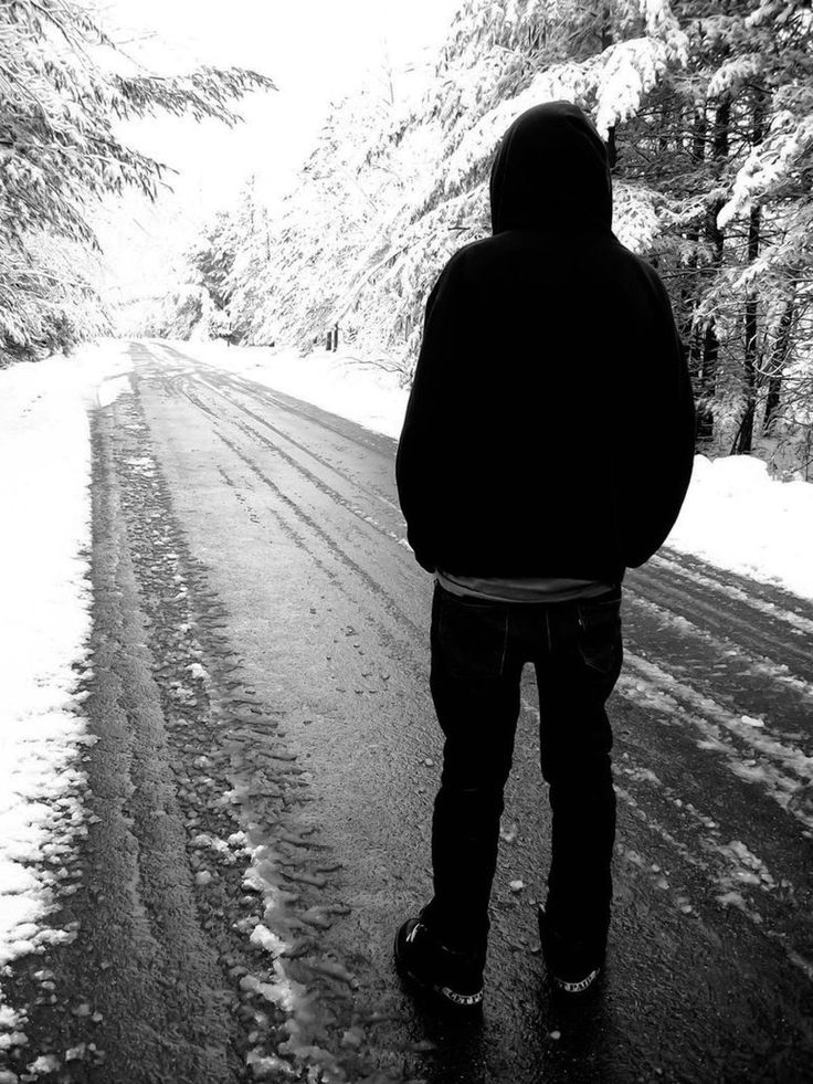 a person standing in the middle of a snowy road with trees on both sides and snow covered ground