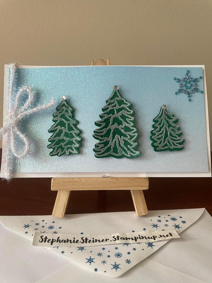 three small christmas trees are on an easel