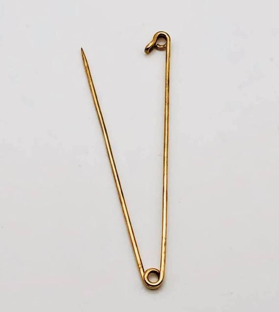 a pair of gold - plated metal scissors on a white surface, one with a hook and the other without