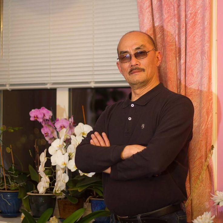 a man standing in front of a window with his arms crossed and looking at the camera