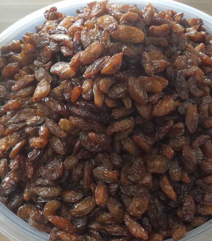 a bowl filled with raisins sitting on top of a wooden table